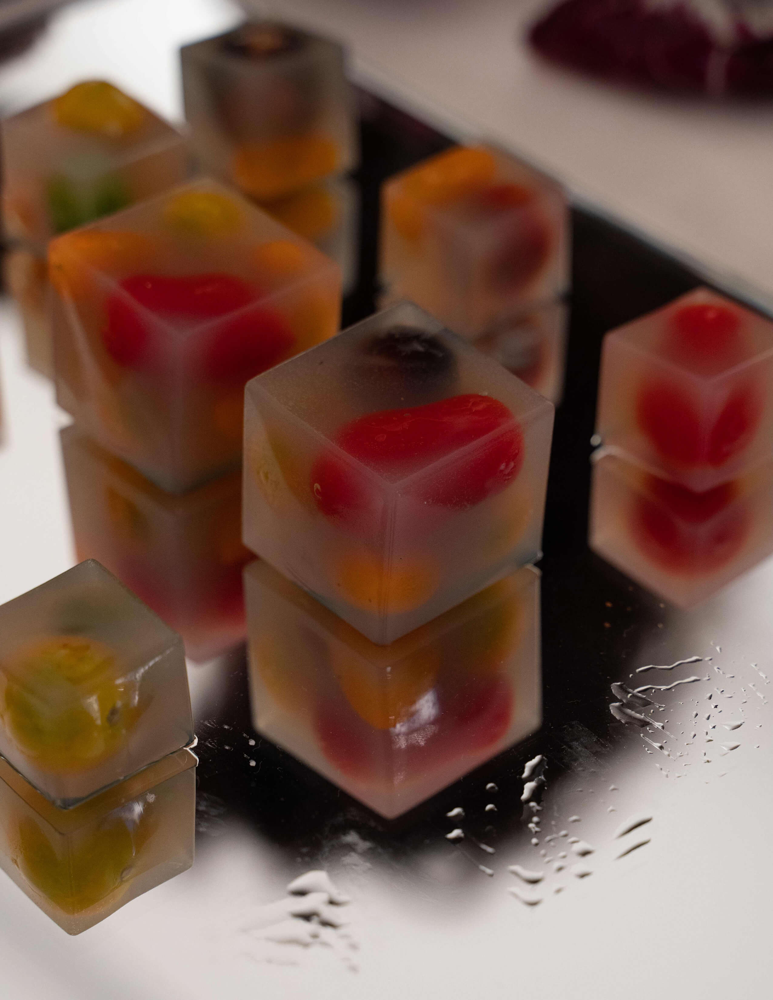 A closer look at jelly cubes served on glass board photographs.