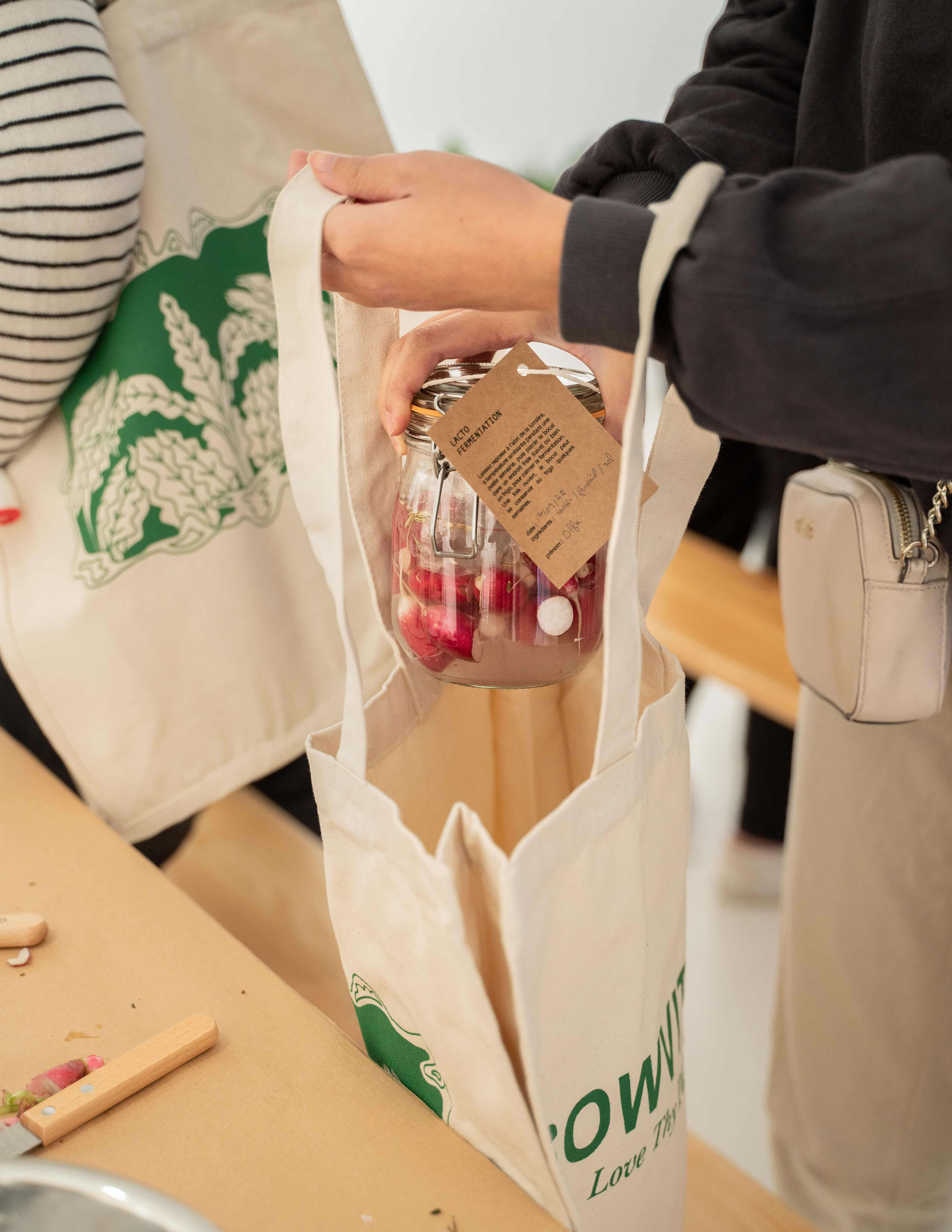 A person puts the jar containing fermented ingredients in the tote bag that is labelled with the Sowvital brand on it.