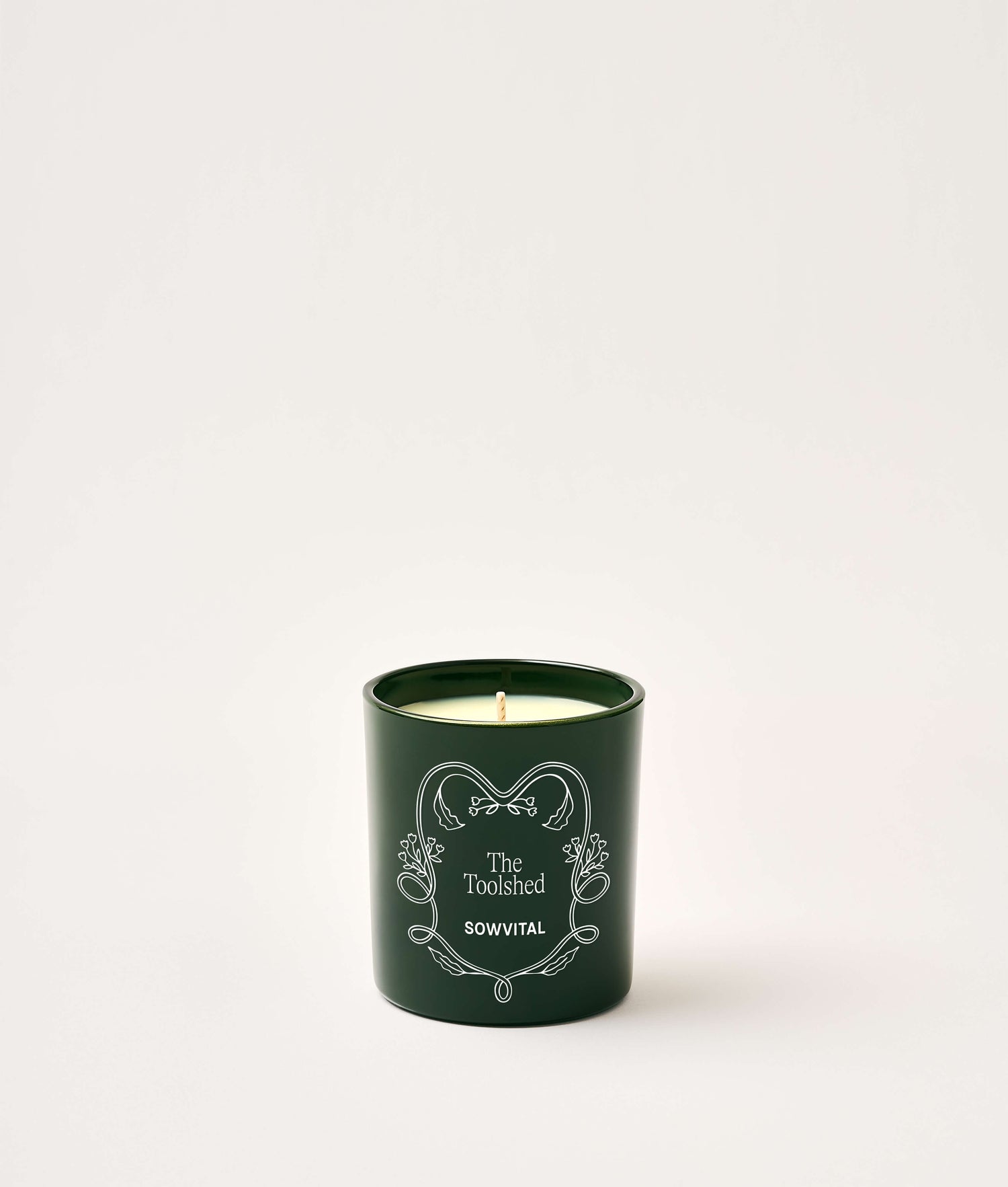 Green candle with decorative text on a white background