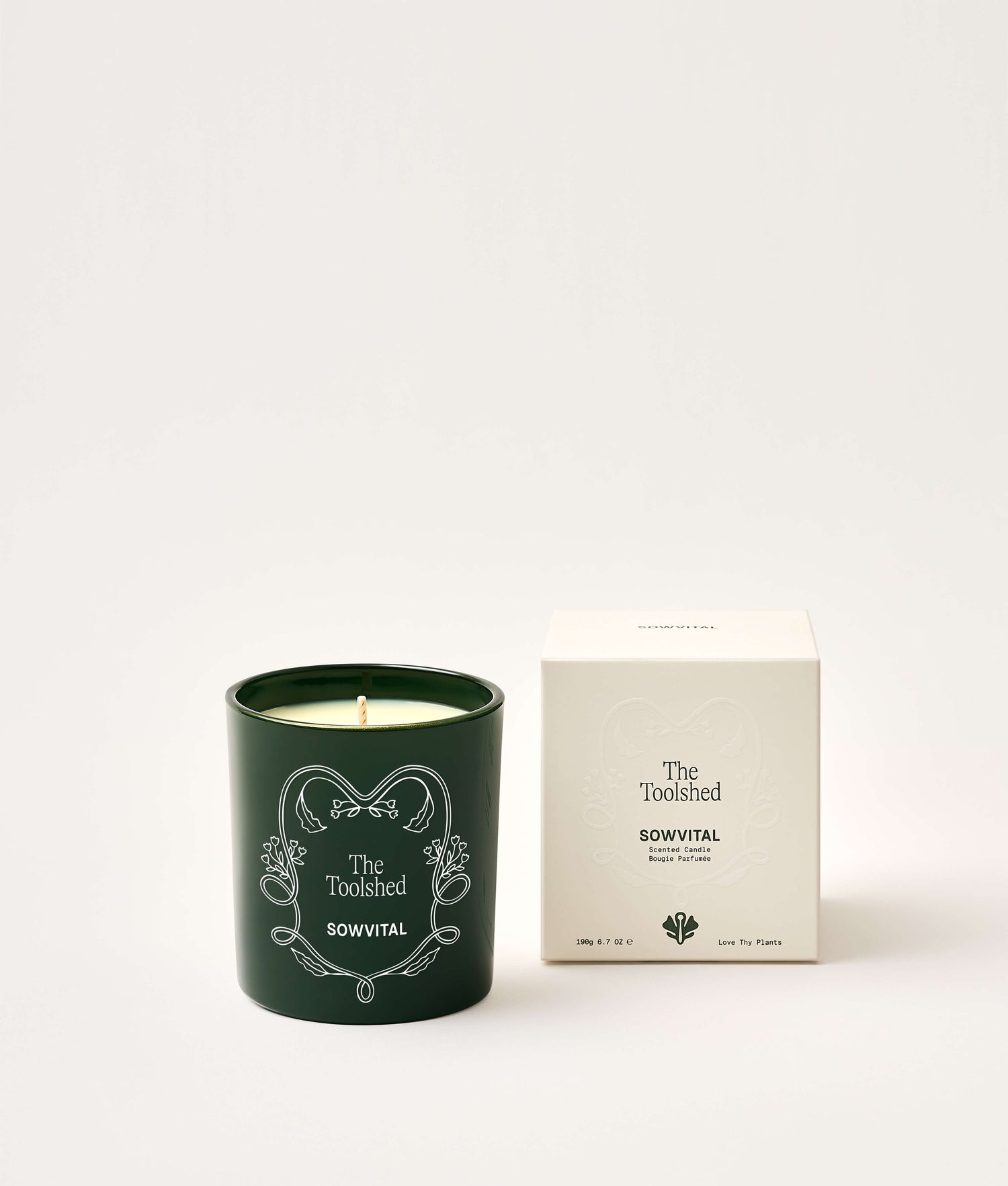 Green candle with decorative design and matching box on a white background