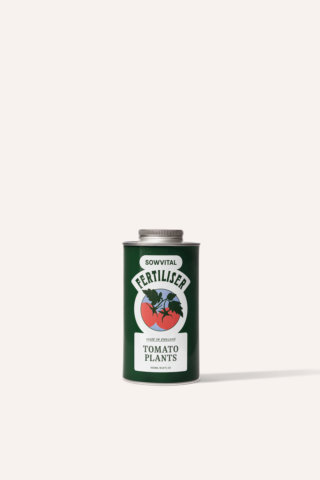 A tall round dark green metal tin of garden tomato plant fertiliser in front of a beige background.