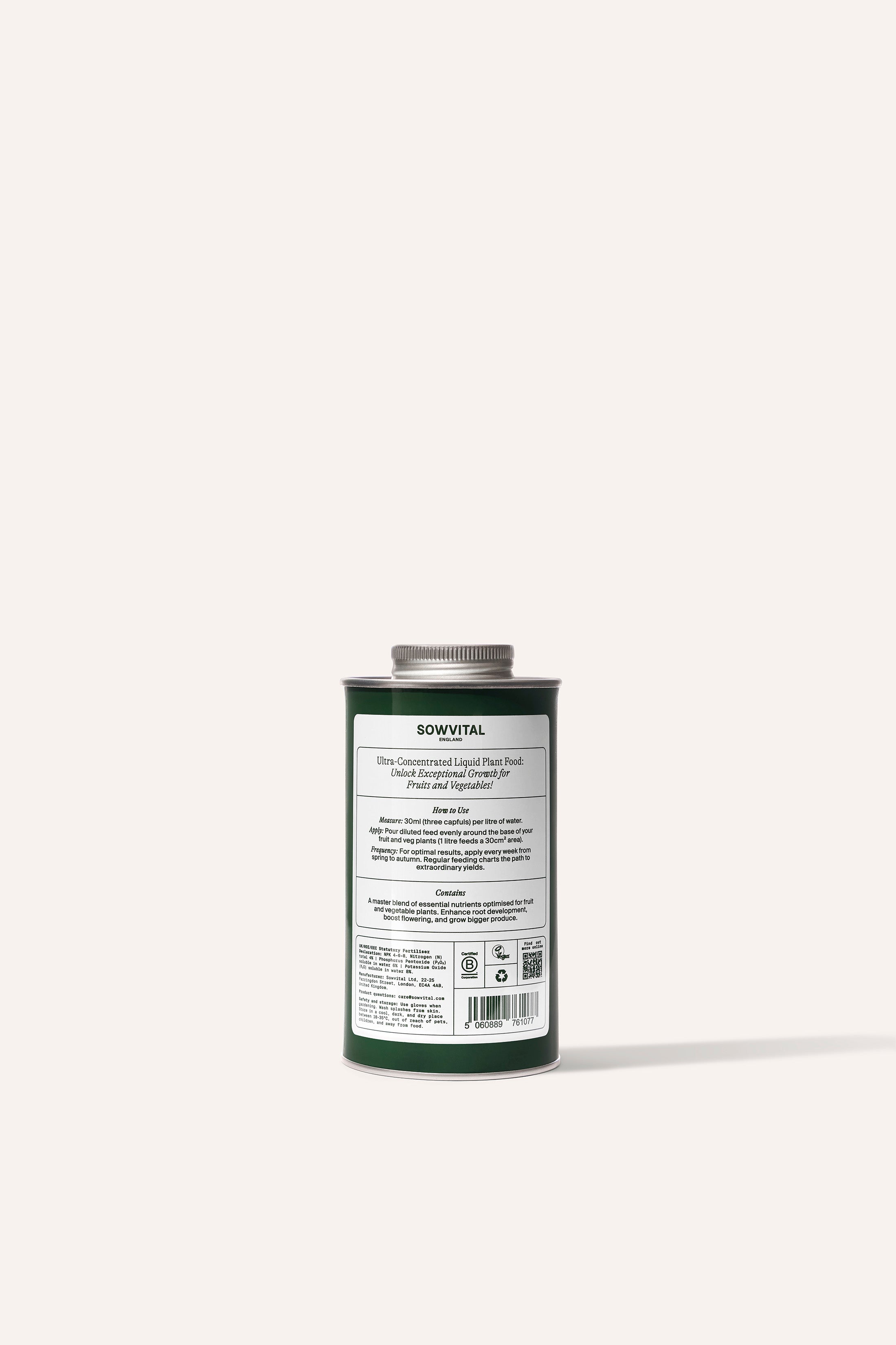 A tall round dark green metal tin of garden fruit & vegetable plant fertiliser in front of a beige background.