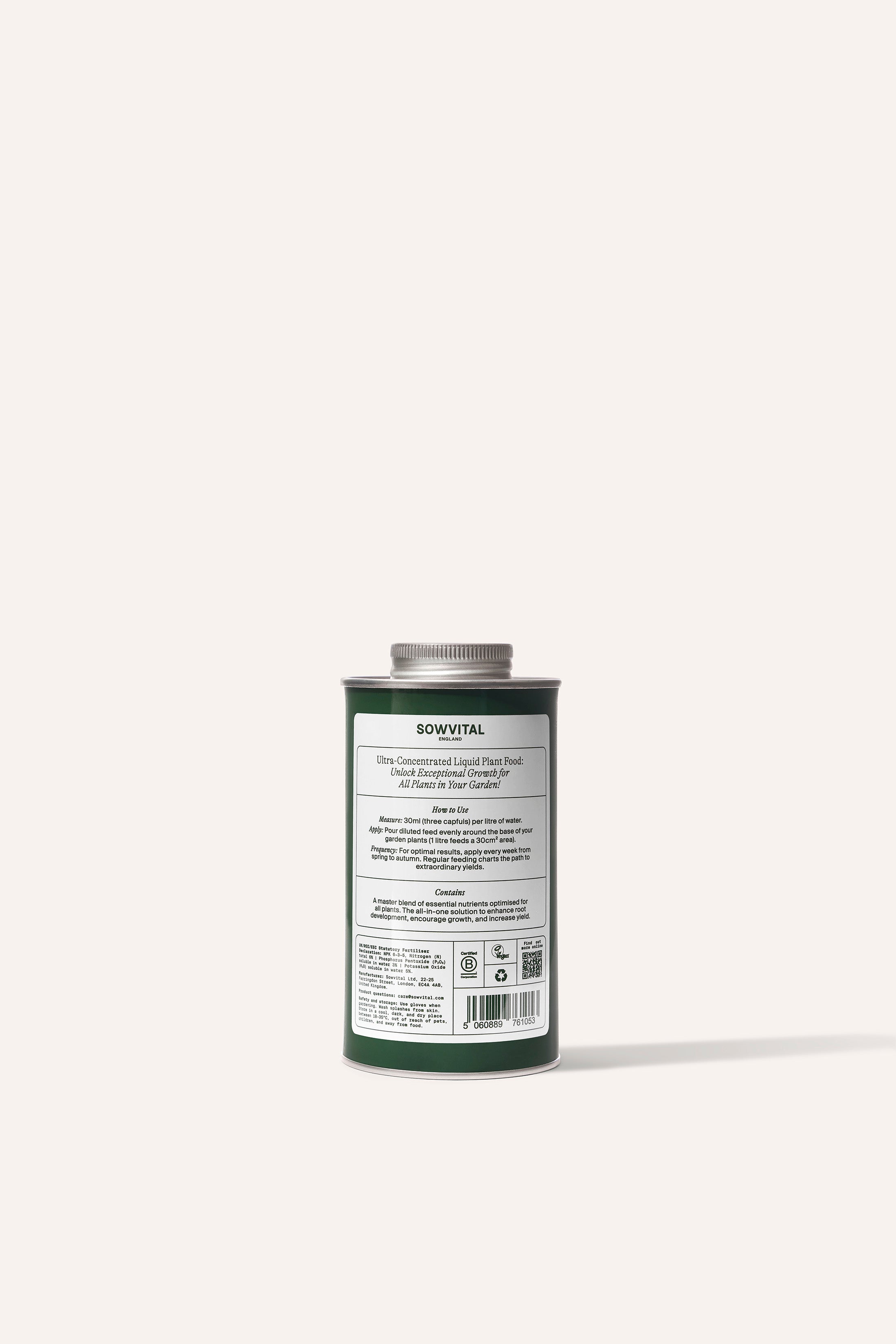 A tall round dark green metal tin of garden multi purpose fertiliser in front of a beige background.
