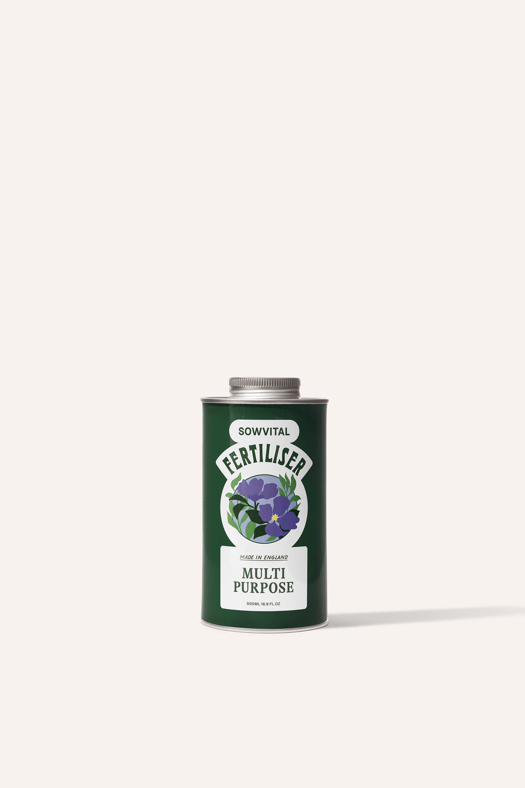 A tall round dark green metal tin of garden multi purpose fertiliser in front of a beige background.
