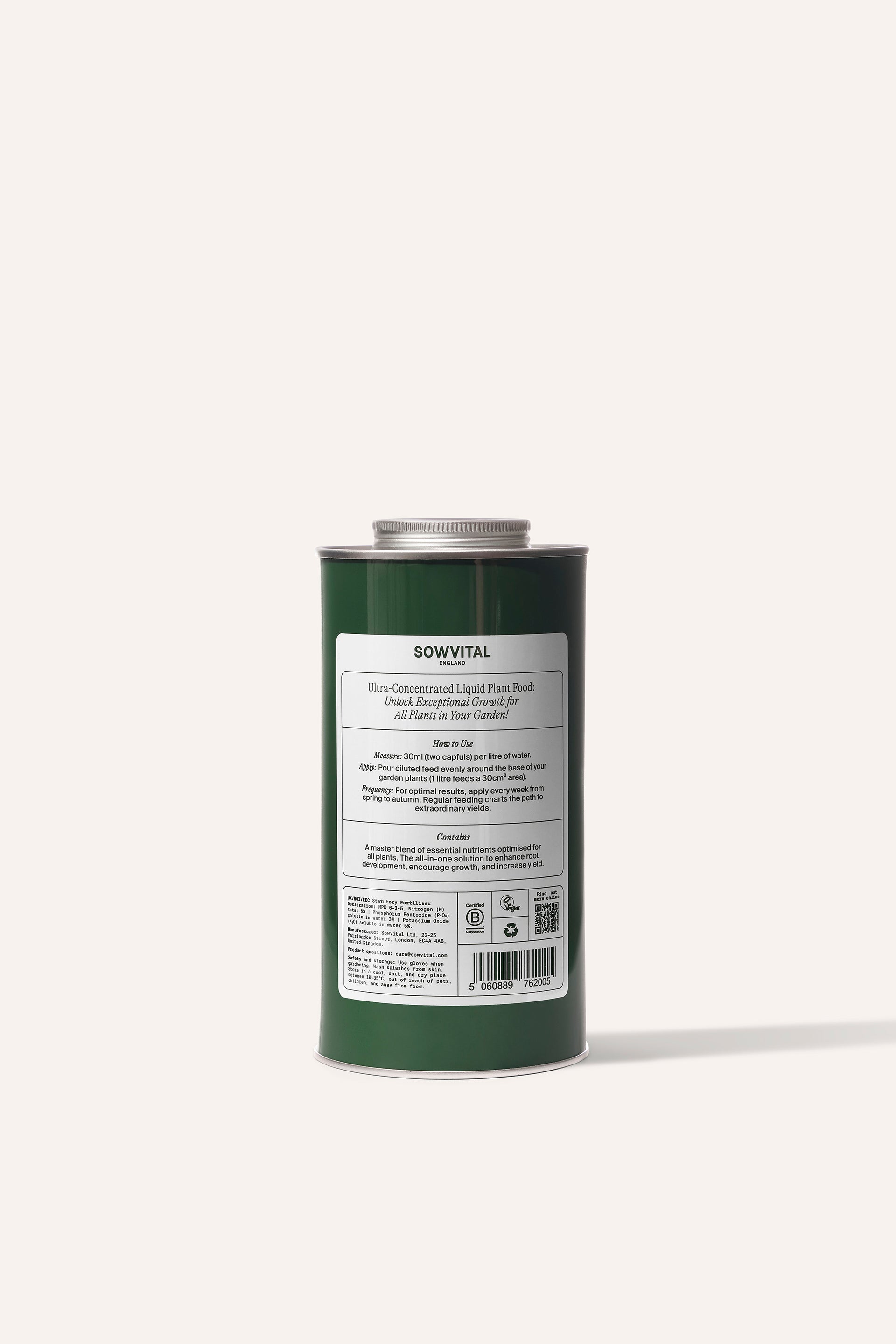 A tall round dark green metal tin of garden multi purpose fertiliser in front of a beige background.