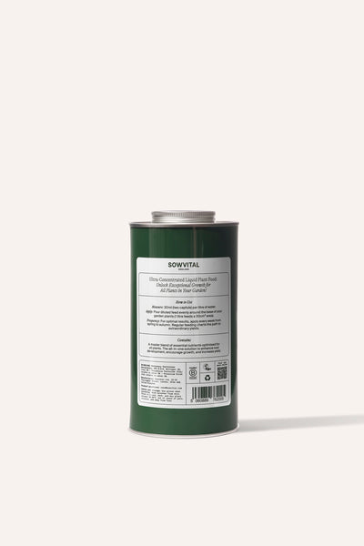 A tall round dark green metal tin of garden multi purpose fertiliser in front of a beige background.
