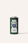 A tall round dark green metal tin of garden multi purpose fertiliser in front of a beige background.