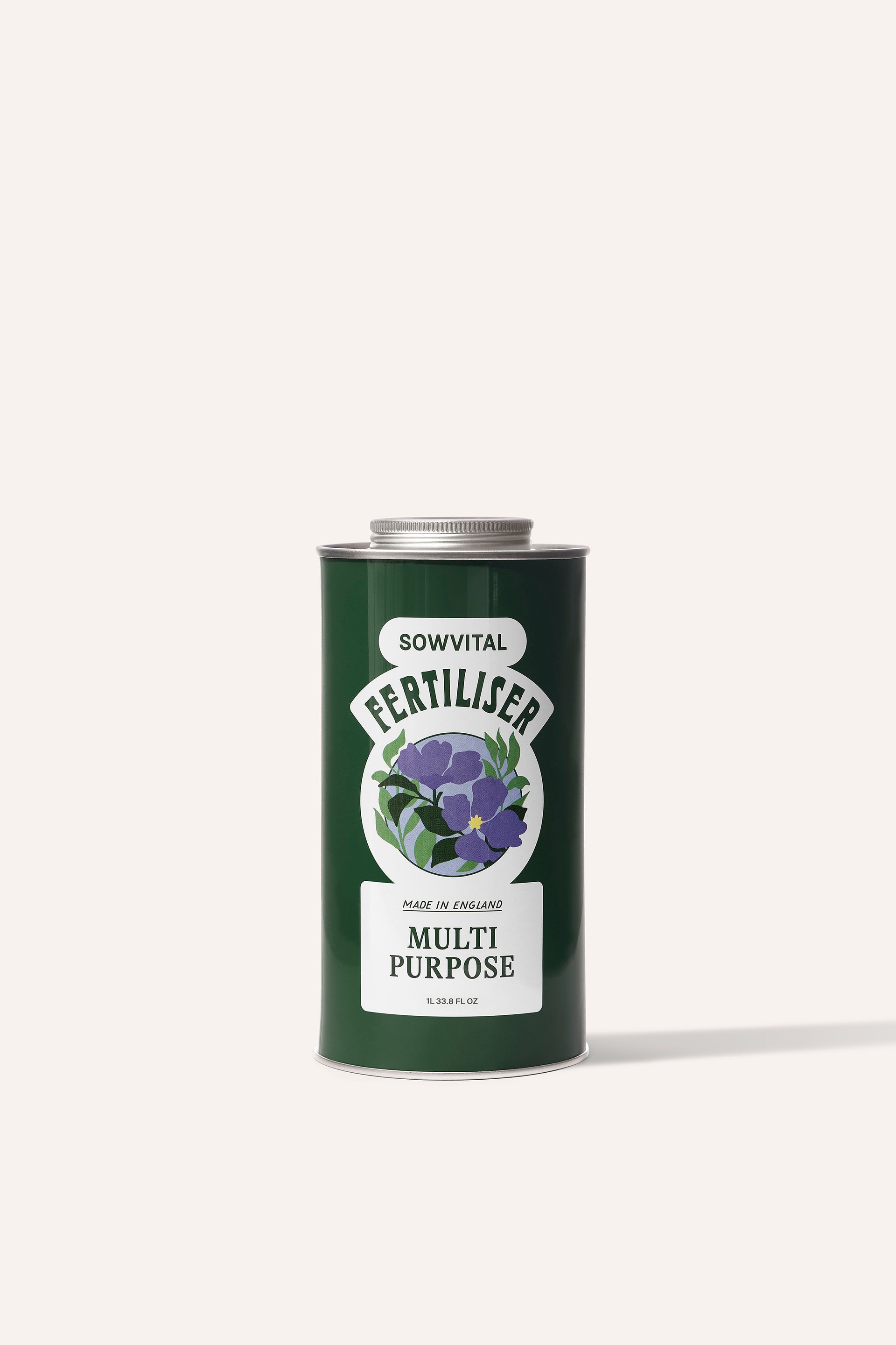A tall round dark green metal tin of garden multi purpose fertiliser in front of a beige background.