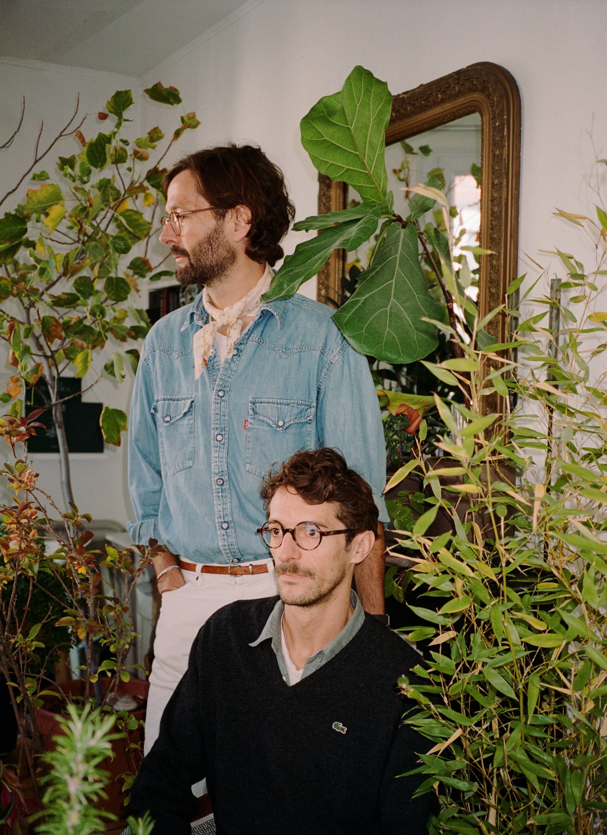 A photograph of Mathias and Geoffery with a collection of their house plants in the room.