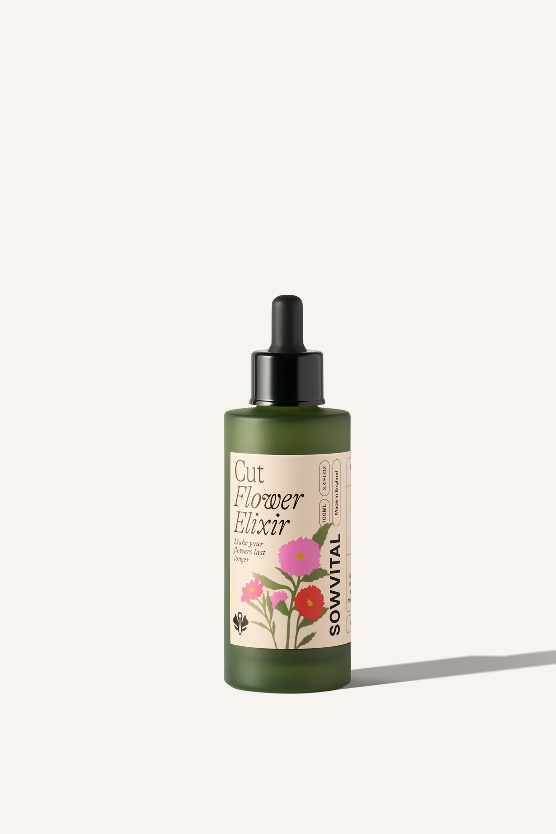 Sowvital's Cut Flower Elixir, a 100ml green glass bottle with a beige label. There is a playful floral illustration on the label. The bottle has a pipette dropper lid. The background is beige.