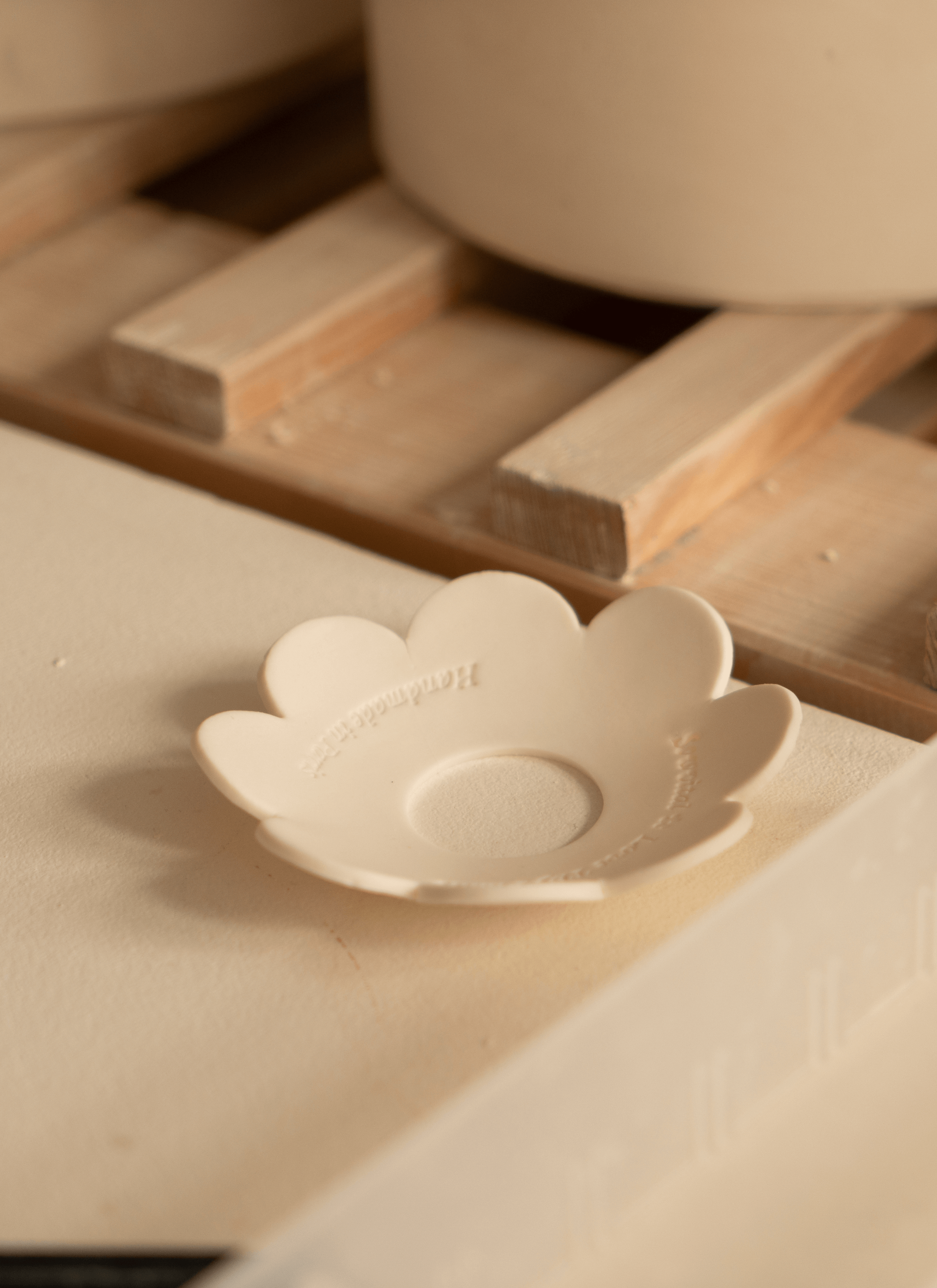 A ceramic germination disc rests on a surface, its smooth texture and earthy tones highlighting its craftsmanship. Nearby, wooden crates hold an assortment of ceramic pots, their shapes and sizes varying.