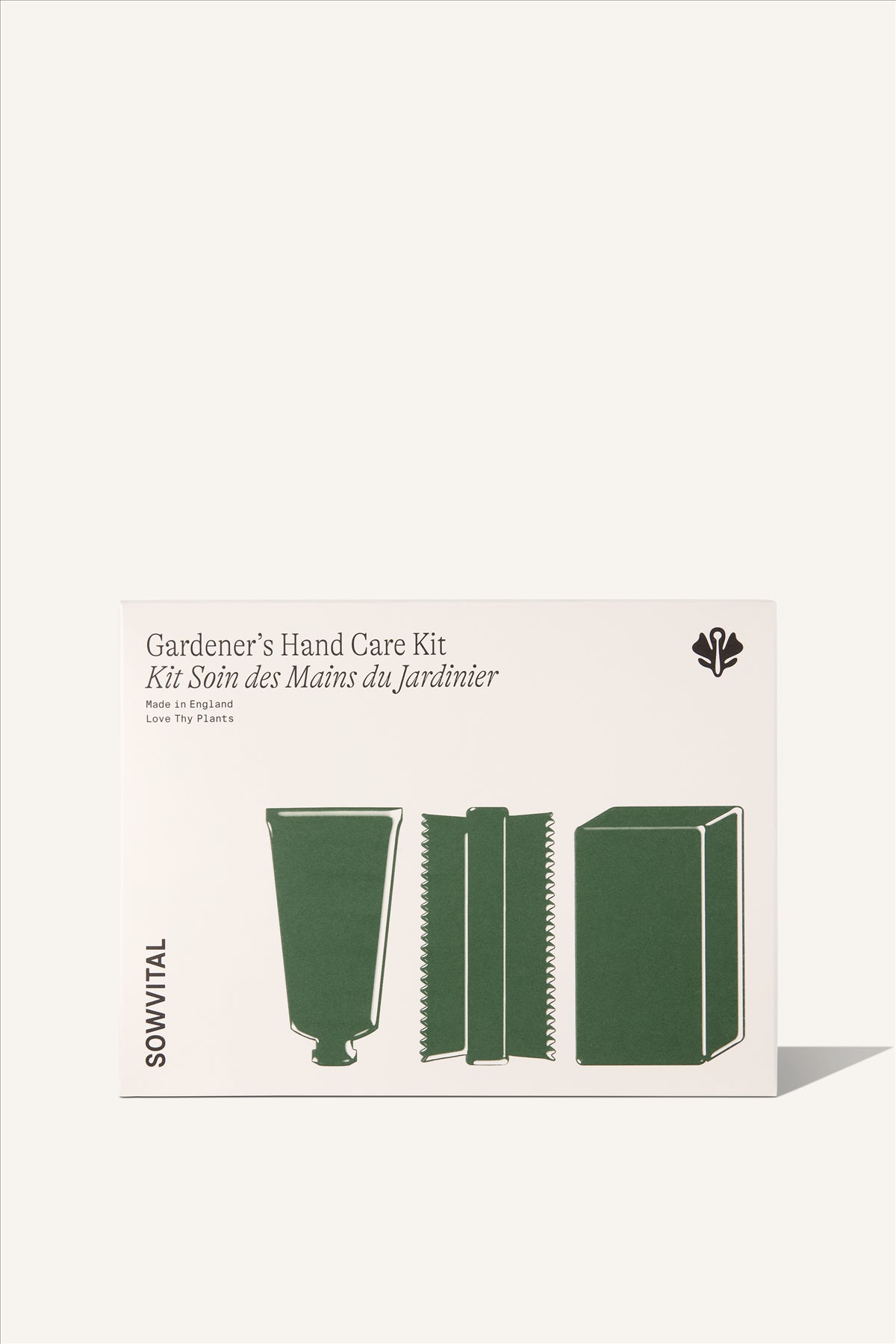 A beige, rectangular fedrigoni paper box, embossed with three green illustrations showing the products within. The Gardener's Hand Care kit. The illustrations show a hand cream tube, a nail brush, and a bar of soap. The background is beige.