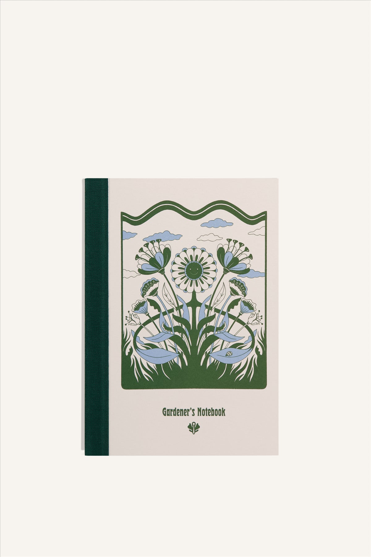 An A6 notebook with a beige cover and green cloth spine. The cover shows a green and blue illustration of a smiling flower in grass, with clouds in the background. The background of the image is beige.