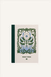 An A6 notebook with a beige cover and green cloth spine. The cover shows a green and blue illustration of a large, blooming flower, with a delicate botanical border. The background of the image is beige.