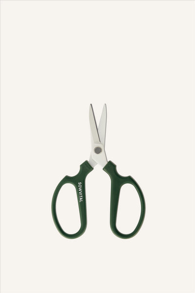 A pair of sharp looking pruning scissors with green handles and white metal blades. The left handle has the SOWVITAL logo written along it. The scissors are in an open position. The background is beige.