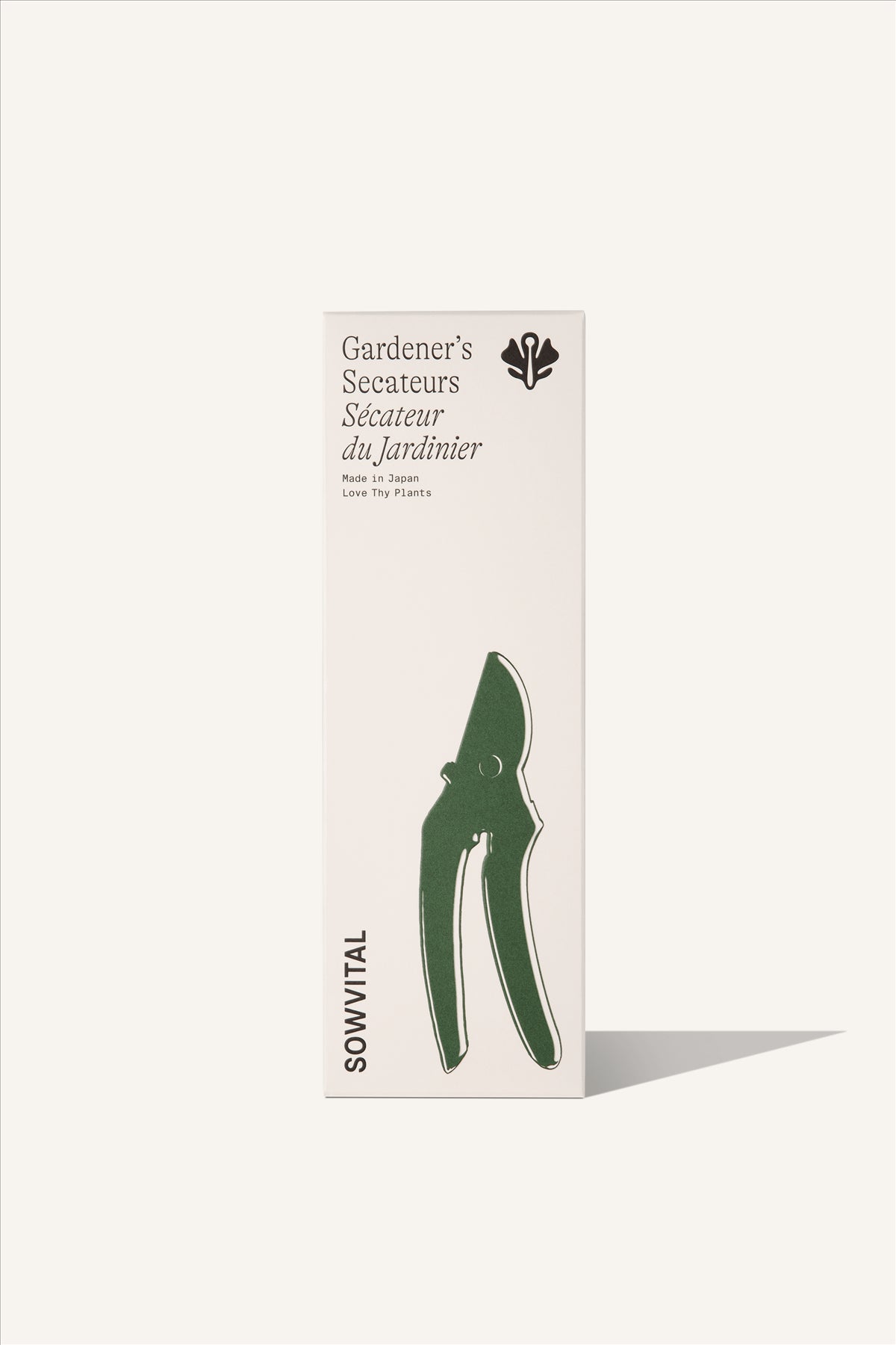 A tall rectangular beige fedrigoni paper box with a green embossed illustration on the front in the shape of the secateurs. The background of the image is beige.