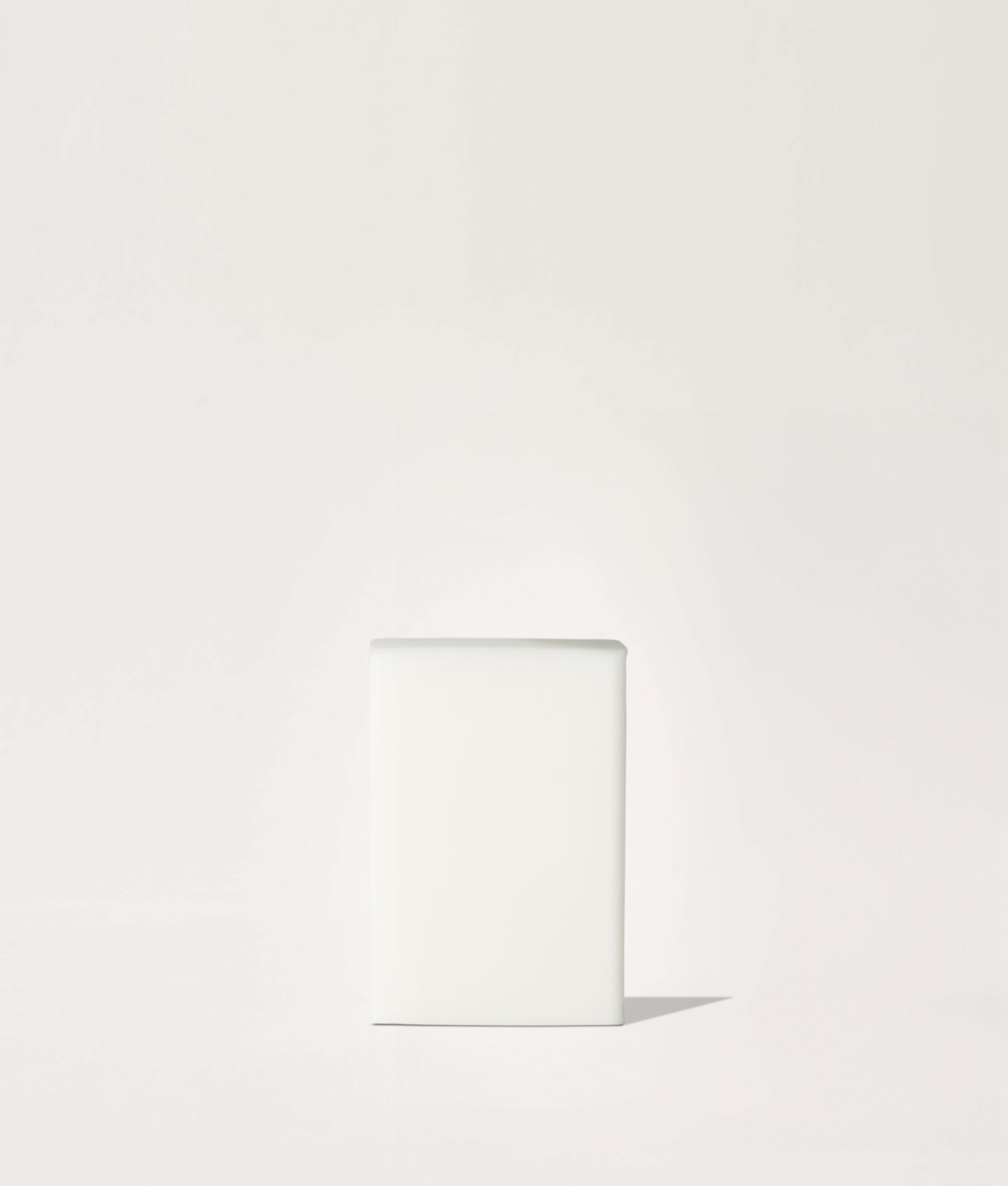 Block of white soap on a light beige background.