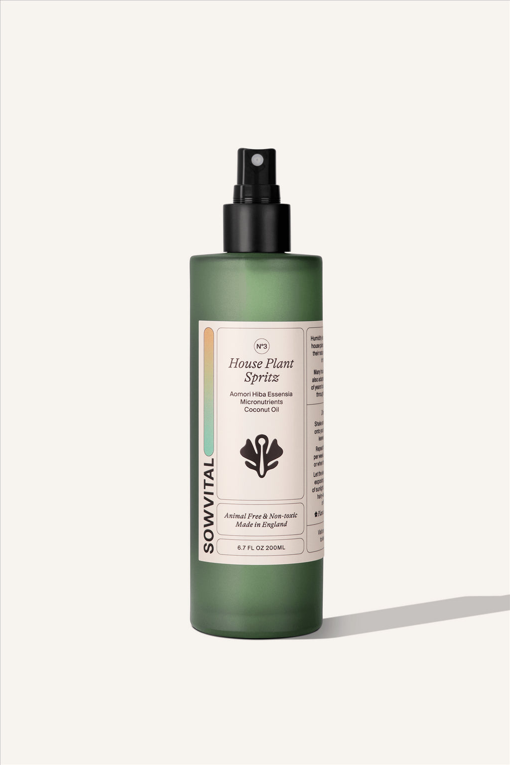 The House Plant Spritz, a 200ml green glass bottle with a black spray top lid and a beige label. The background of the image is beige.