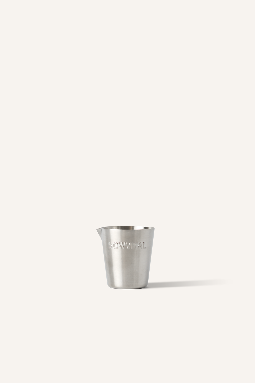 A stainless steel measuring cup with "SOWVITAL" stamped into the side, sat in front of a beige background.