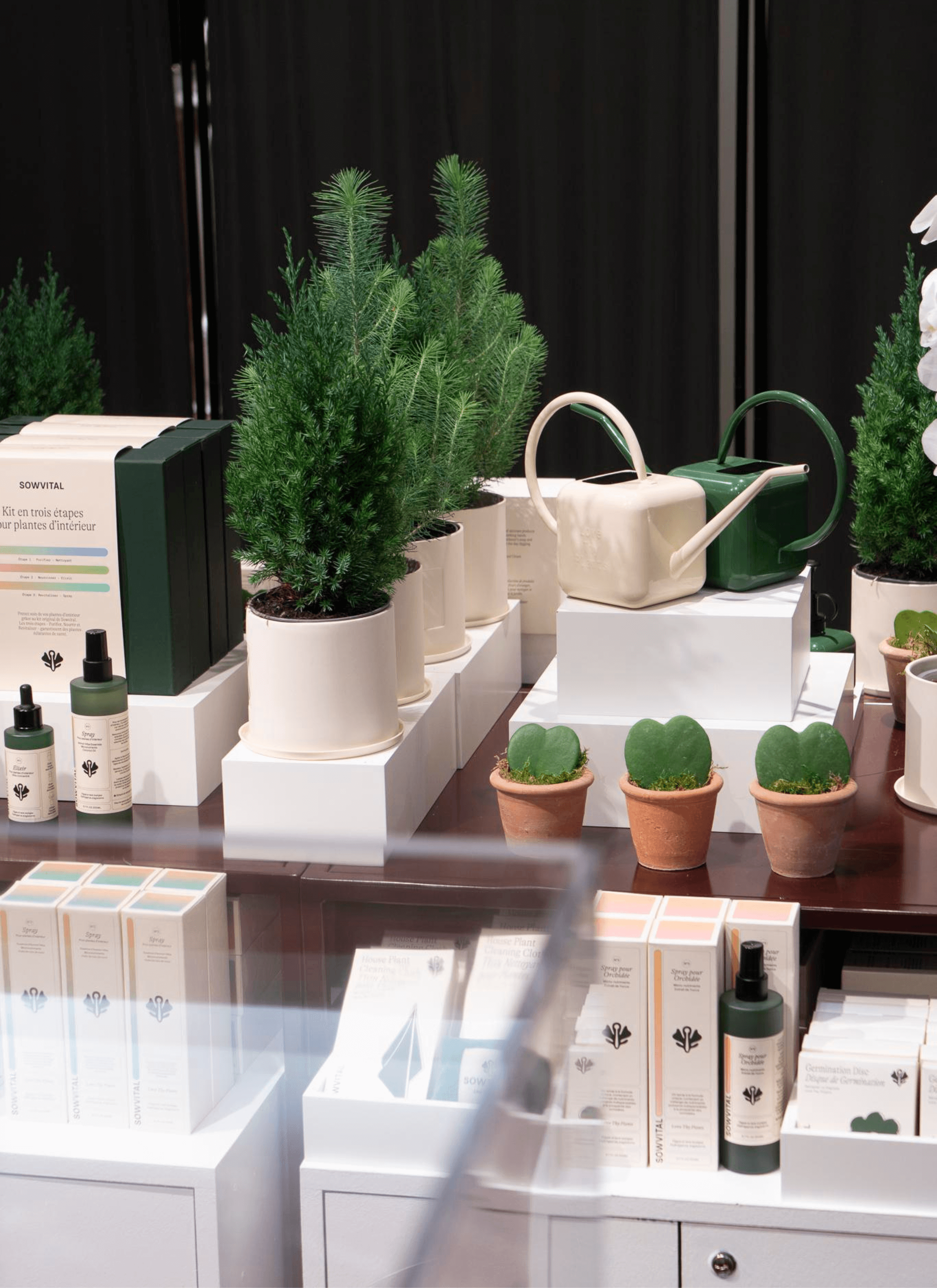 Sowvital products displayed in an open area surrounded by numerous potted plants serving as decorations.