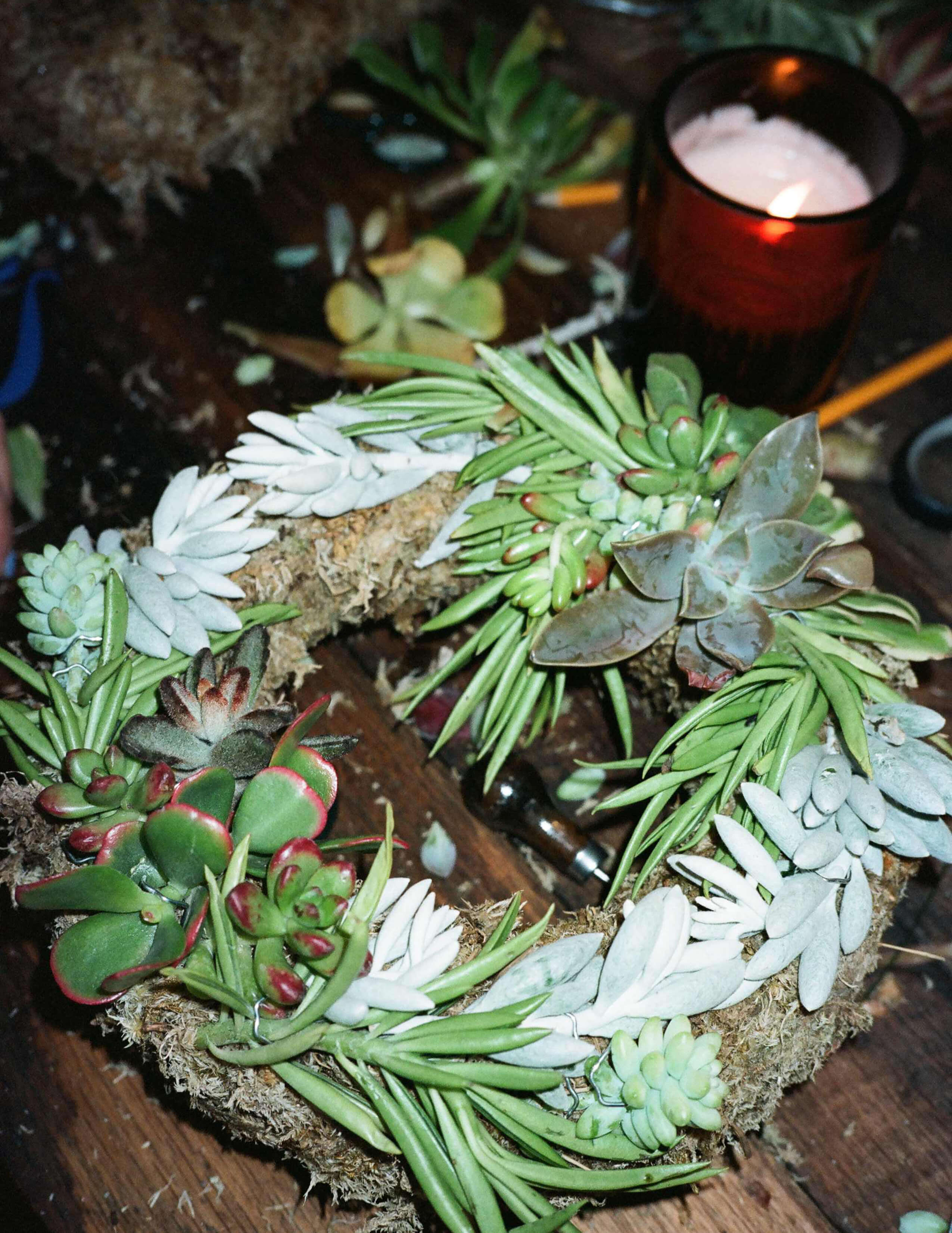 A succulent wreath next to a lightened candle.