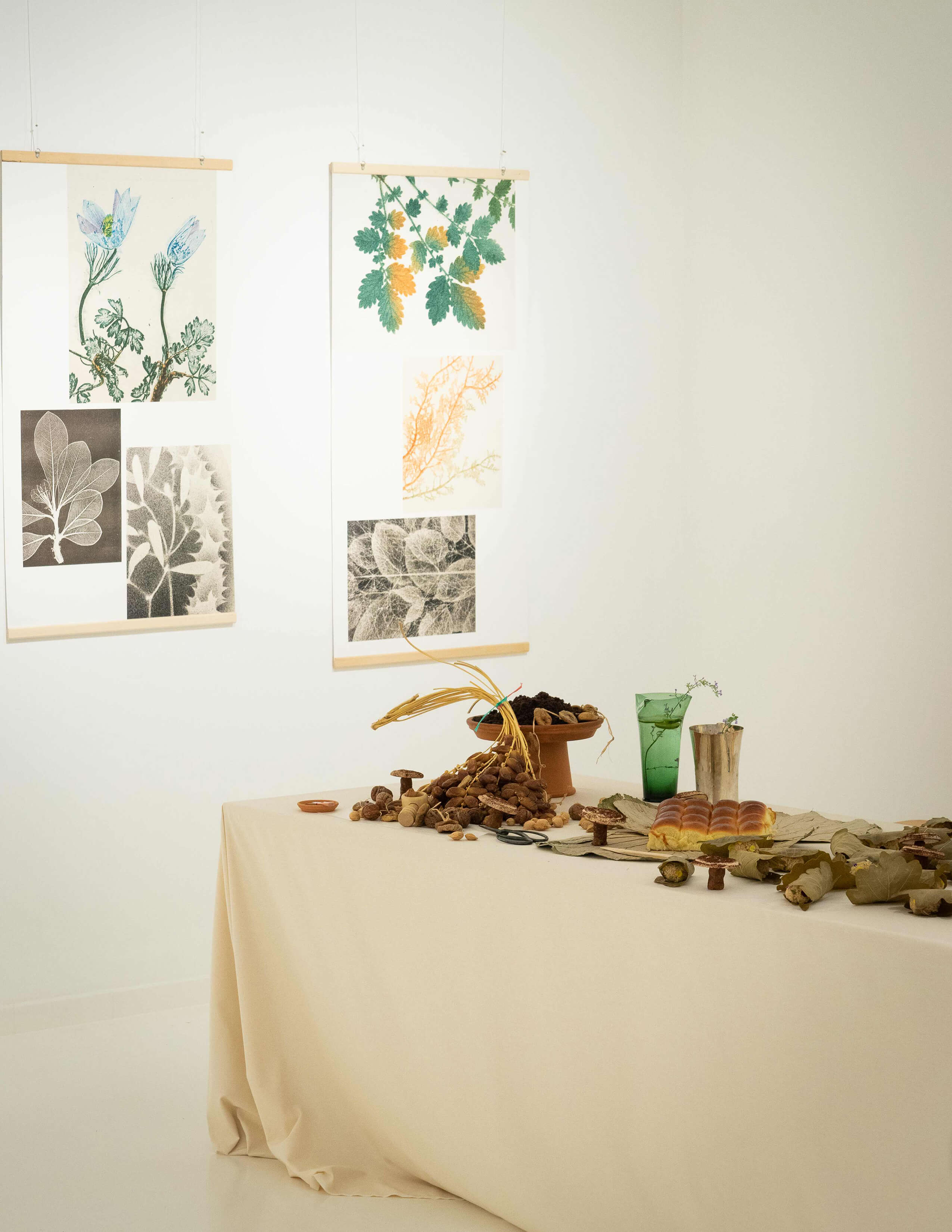 Different kinds of food are presented on the table with white tablecloths and a few pieces of plant-themed paintings hung on the wall.