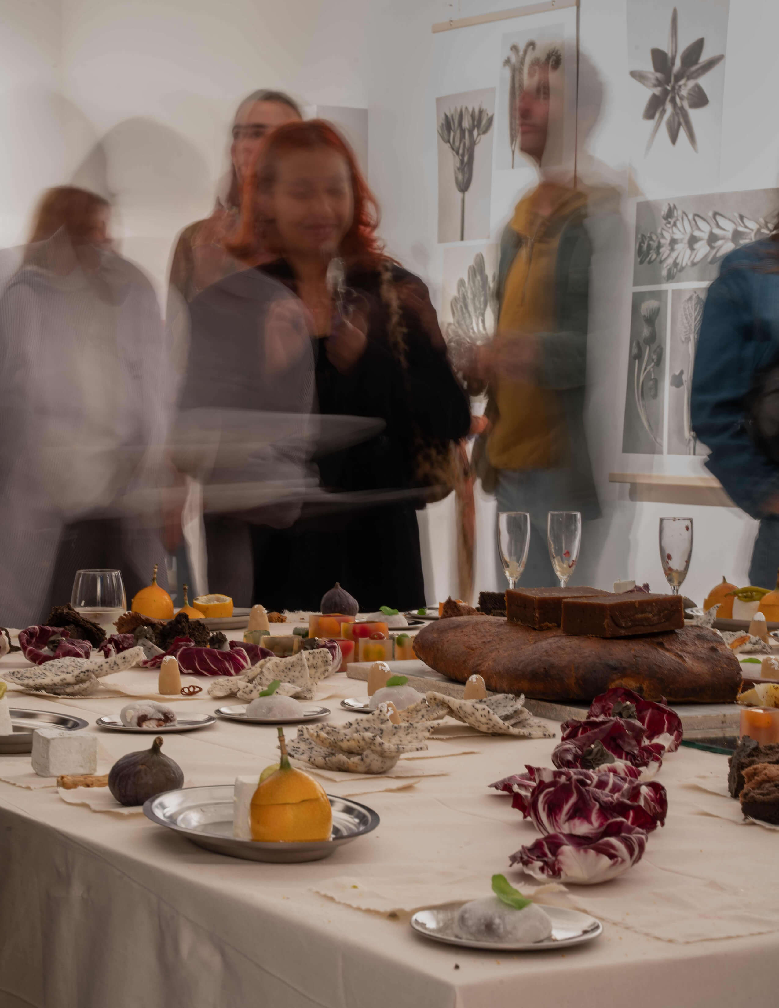 A photograph capturing people’s movement with a table of nicely presented food.