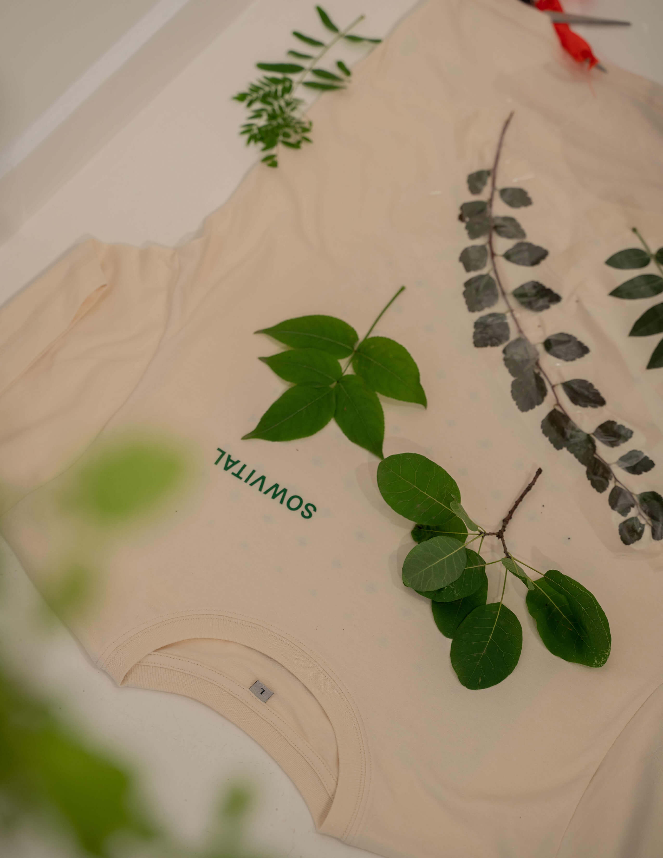Different kinds of plants on a white T-shirt with the Sowvital logo on it.