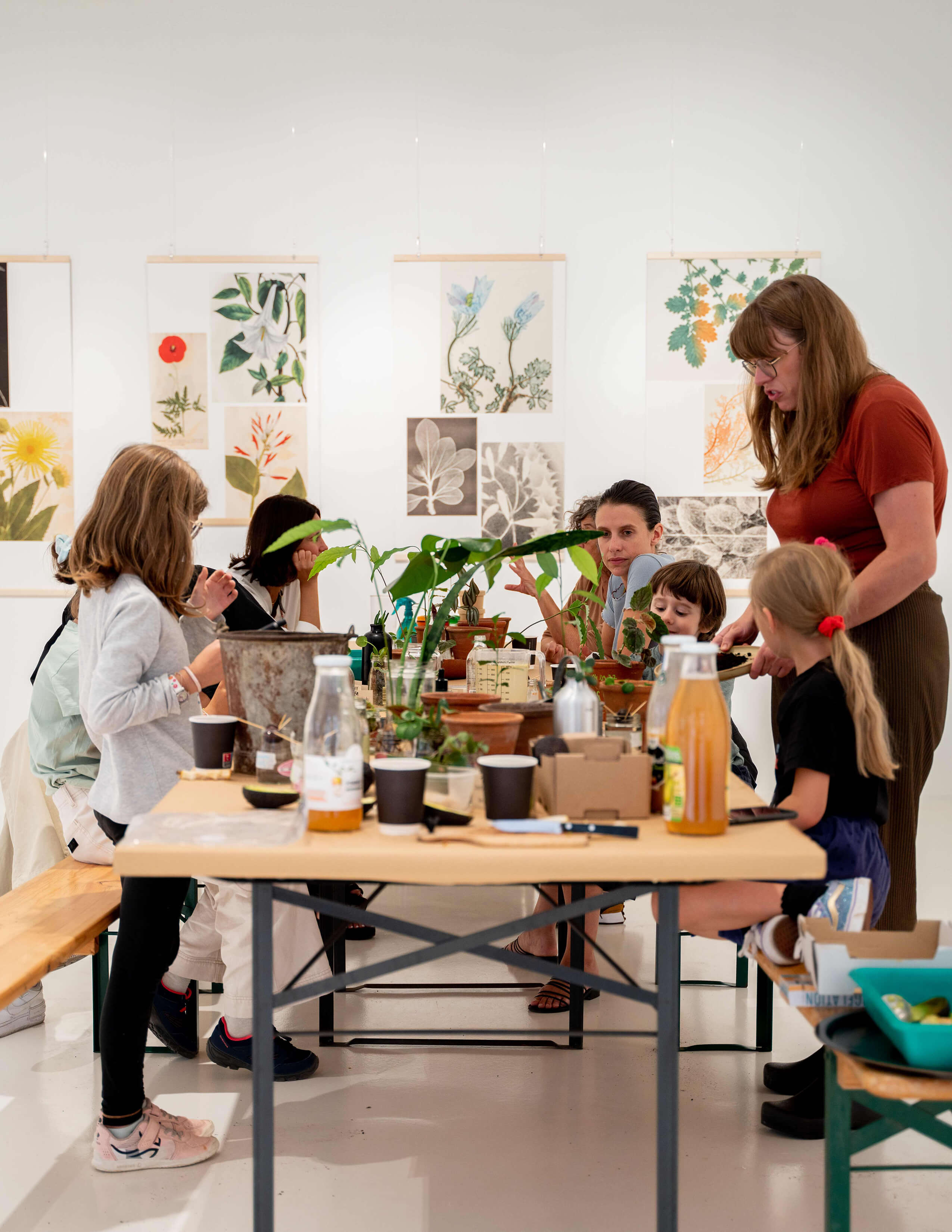 A group of kids with their parents surround the table, which is filled with a load of materials on the surface, ready to have the activity in the workshop.