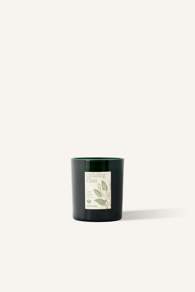 A scented candle in a green glass vessel with a beige and green label.