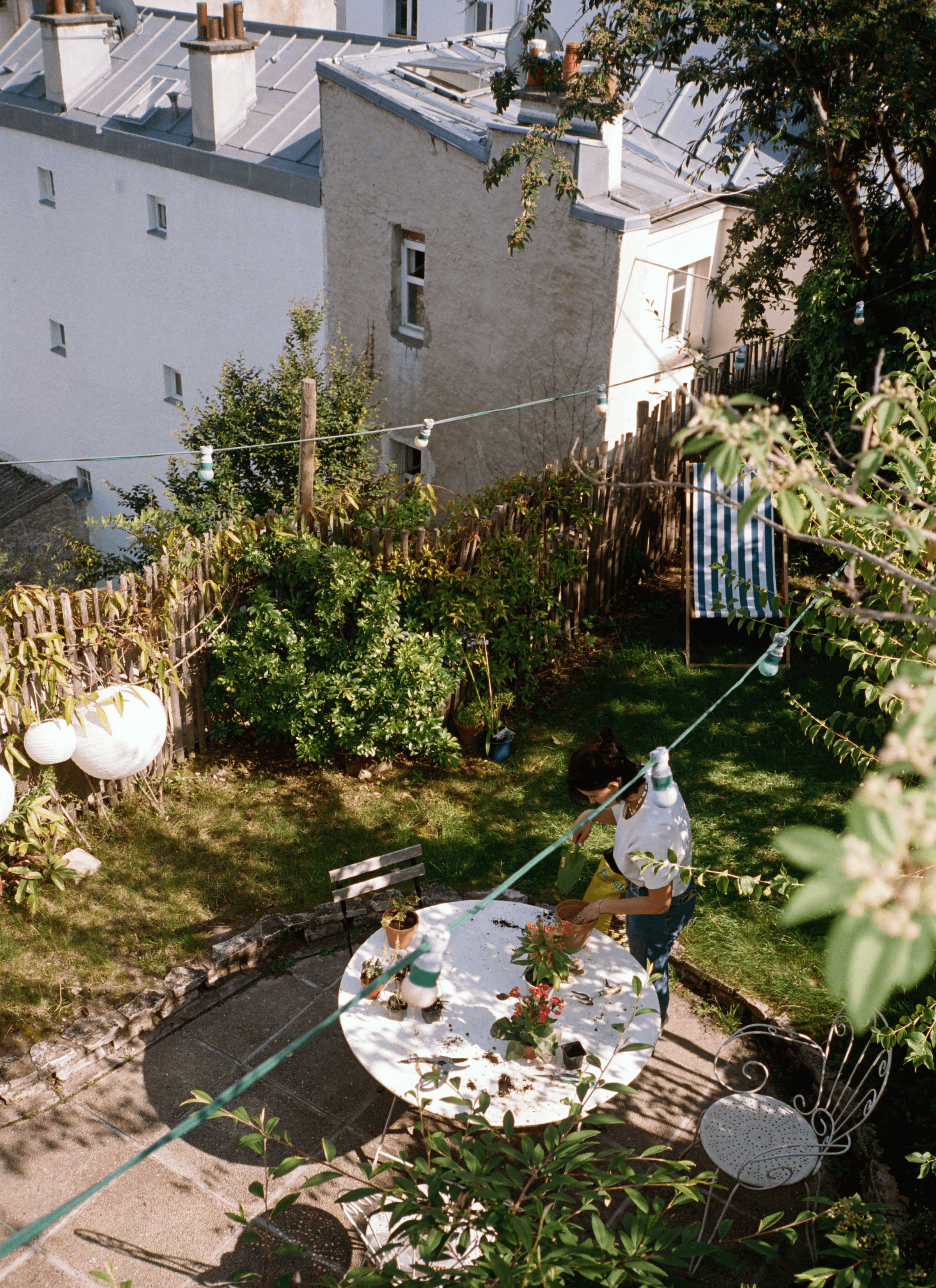 Leslie David growing plants on the table in her full-of-green-plants backyard.