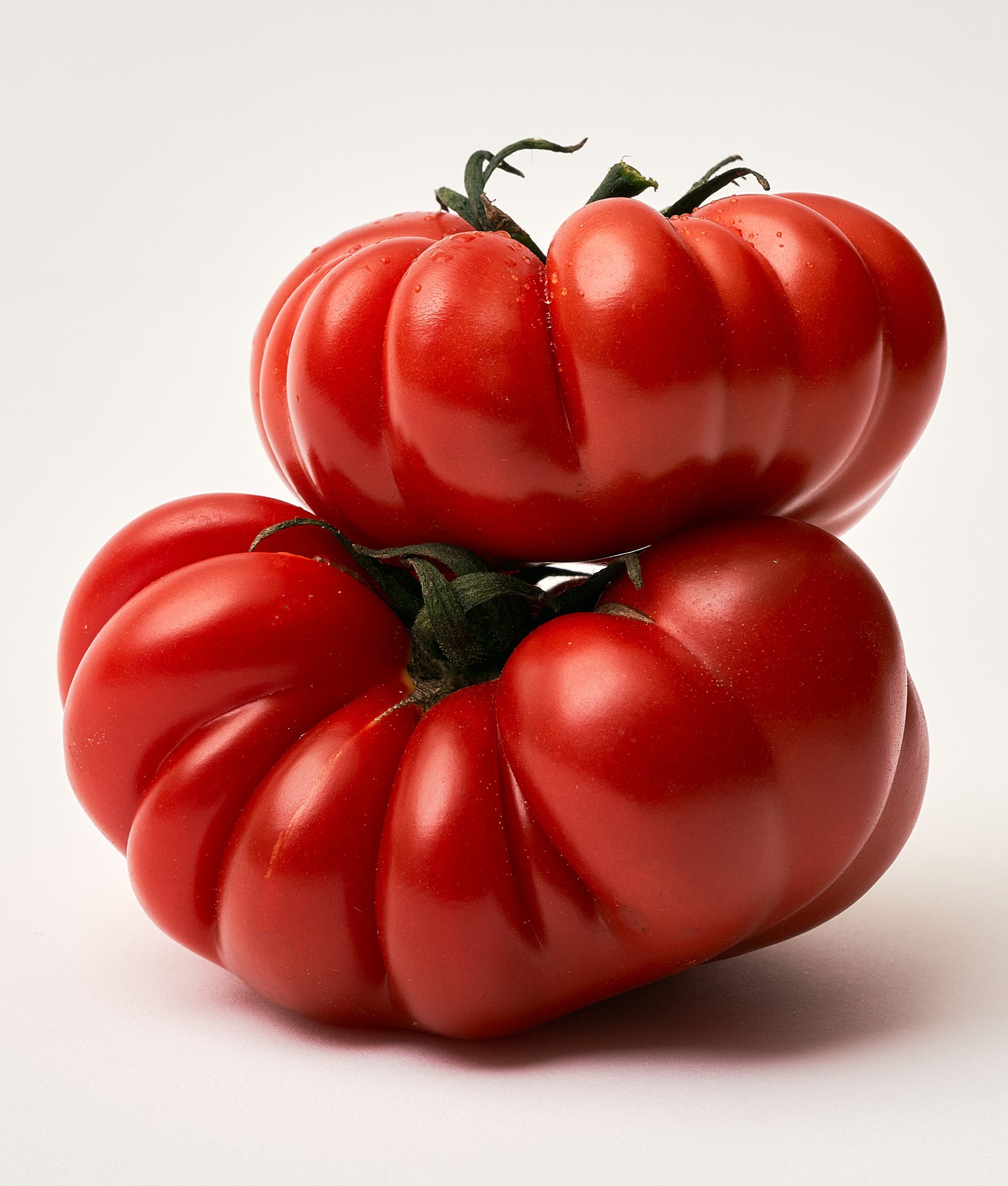 Two large red tomatoes on a white background