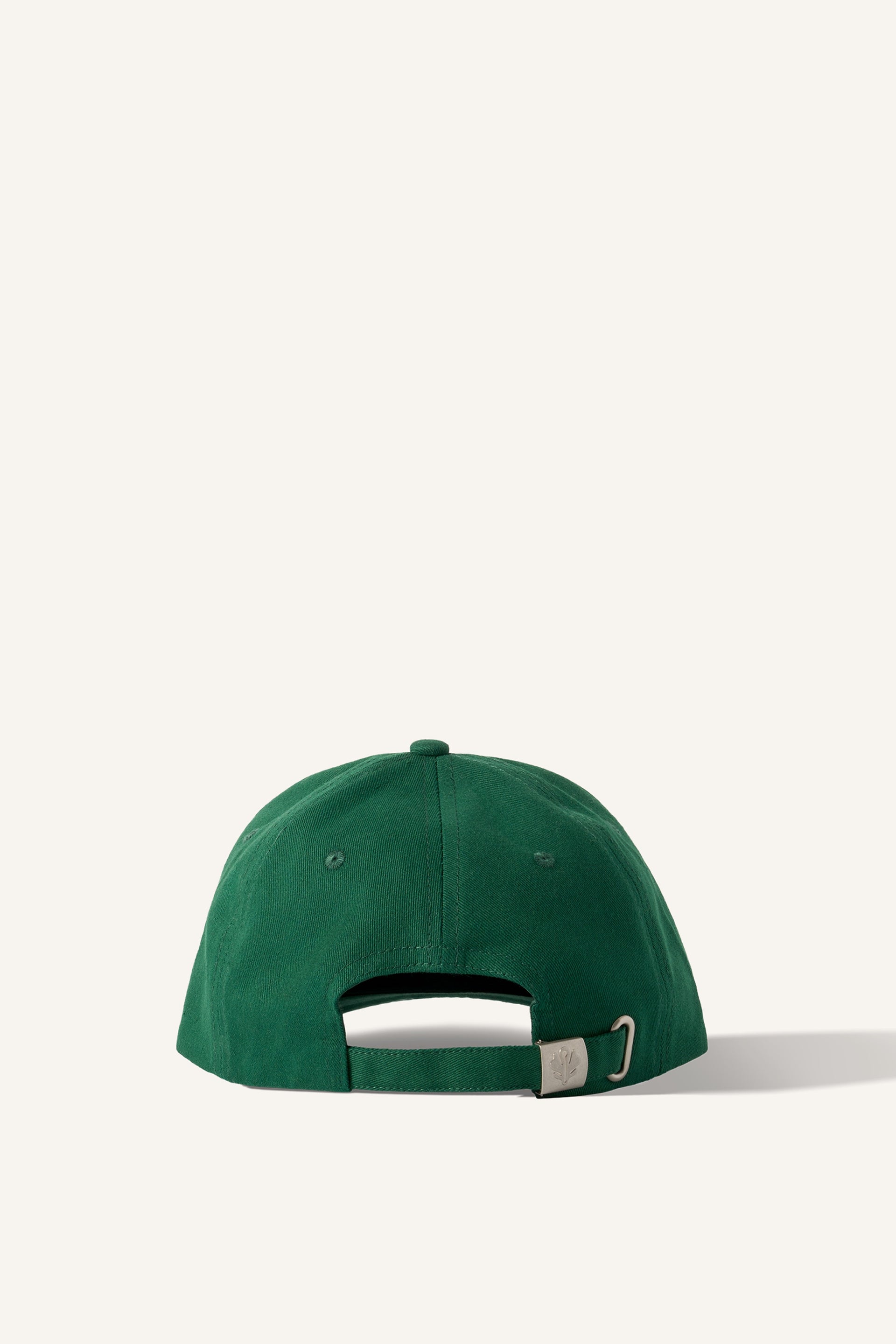 A green baseball cap, made of 100% cotton. Seen from the back, there is an adjustable strap with a metal clasp embossed with the Sowvital logo. The background is beige.