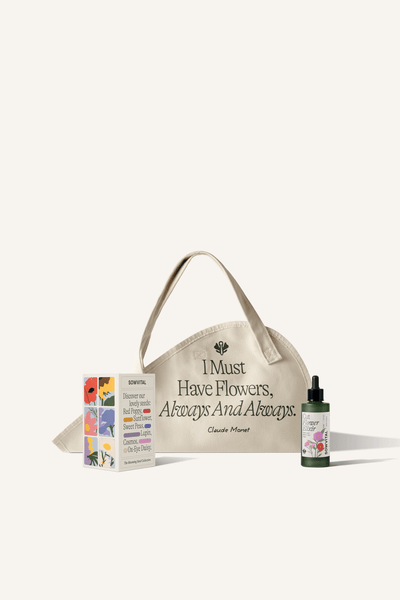 A cotton canvas flower tote with a bouquet of flowers within it. Sat in front is a flower seed collection box and a small bottle of cut flower food.